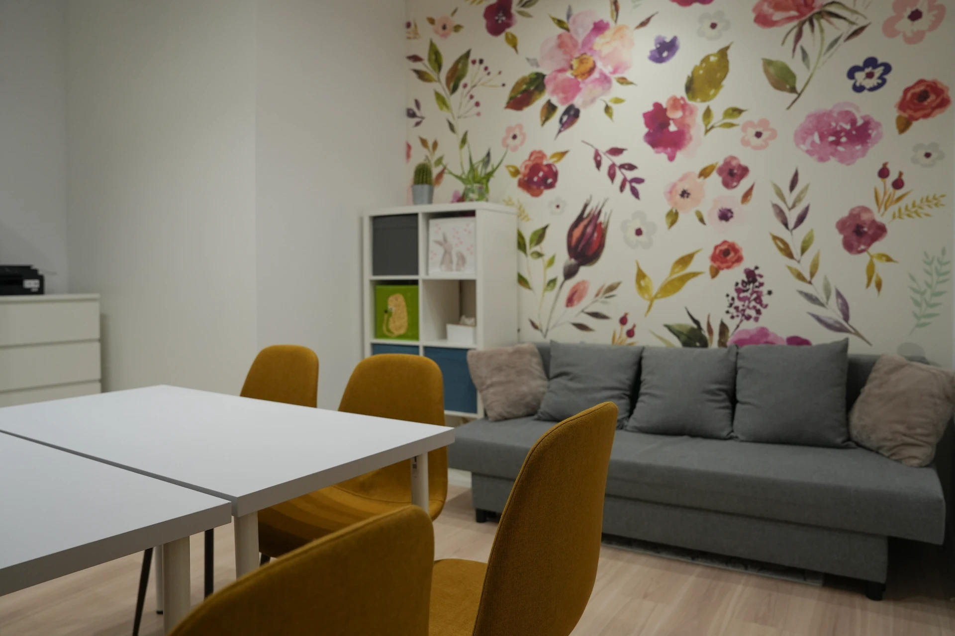 Sala terapeutyczna - stół i sofa z kwiatową tapetą